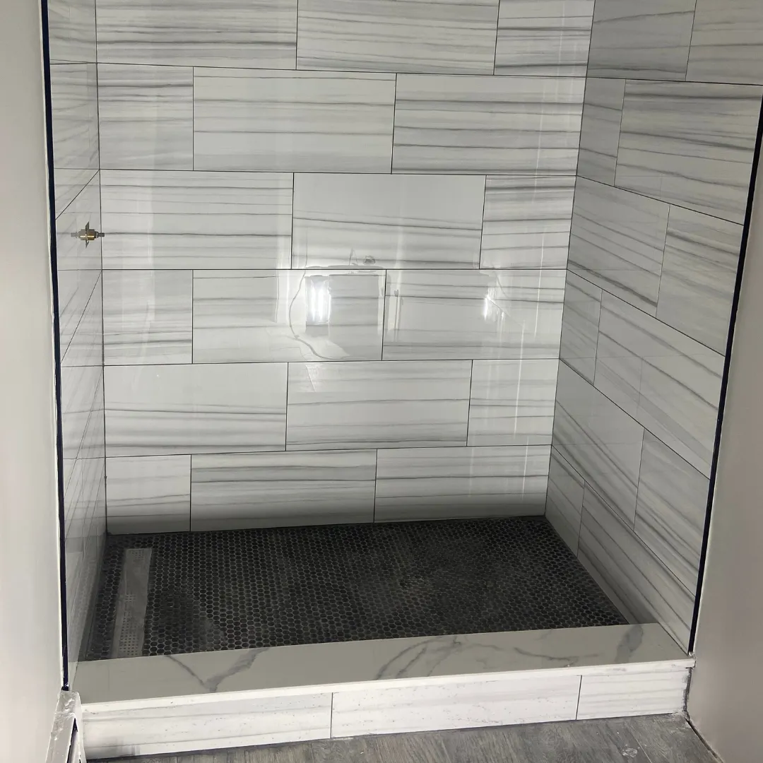 Walk-in shower remodel with white marble walls and black hex penny tile floor by SF Construction in Worcester, MA
