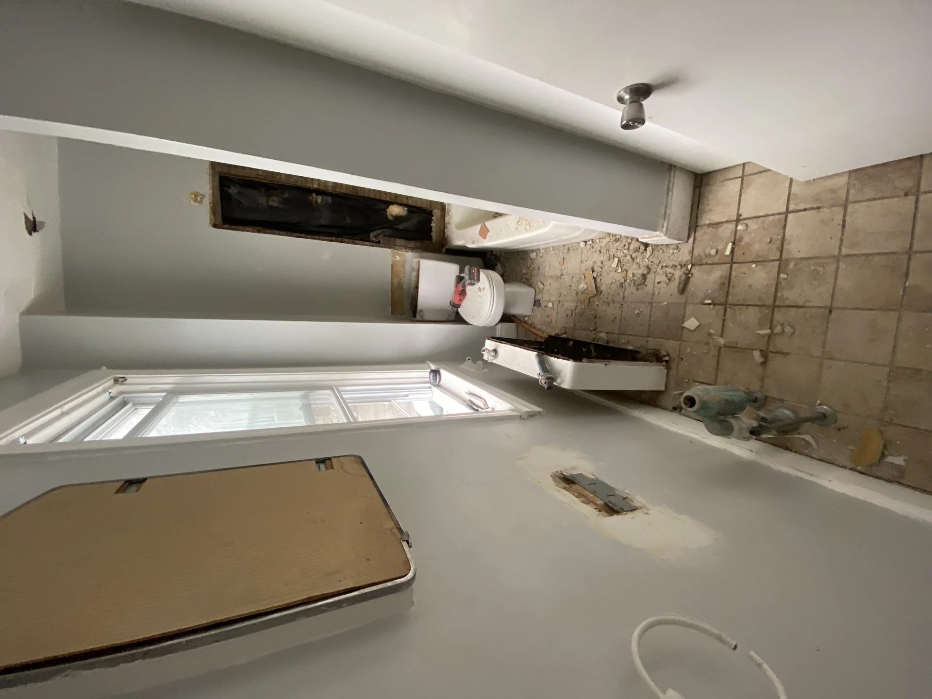 A bathroom undergoing demolition with a toilet, bathtub, and exposed wall sections. by SF Construction in Northborough, MA