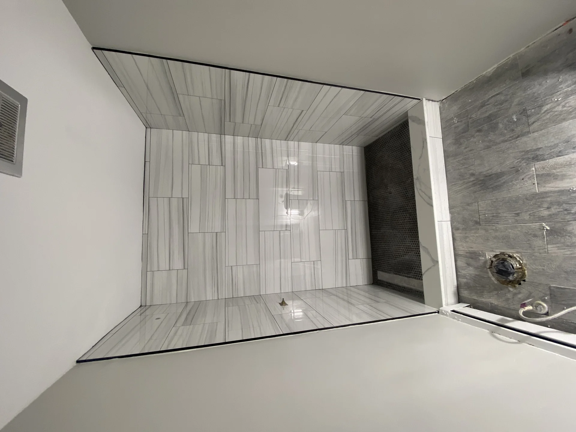 Modern bathroom shower installation with gray tile and glass enclosure by SF Construction in Westborough, MA