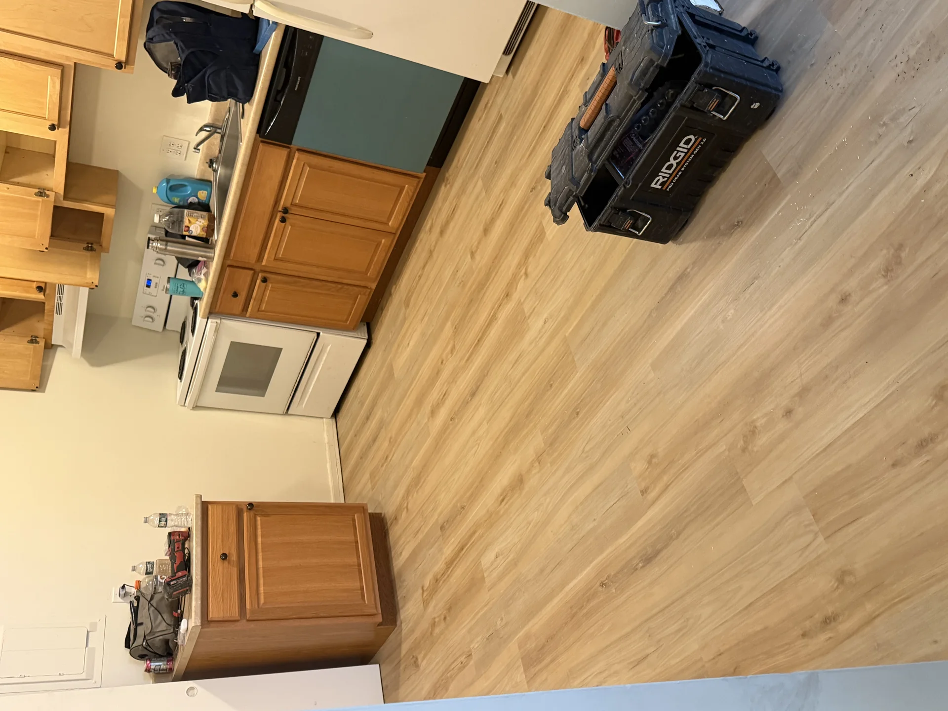 Kitchen with light wood vinyl plank flooring installation in progress by SF Construction in Hudson, MA