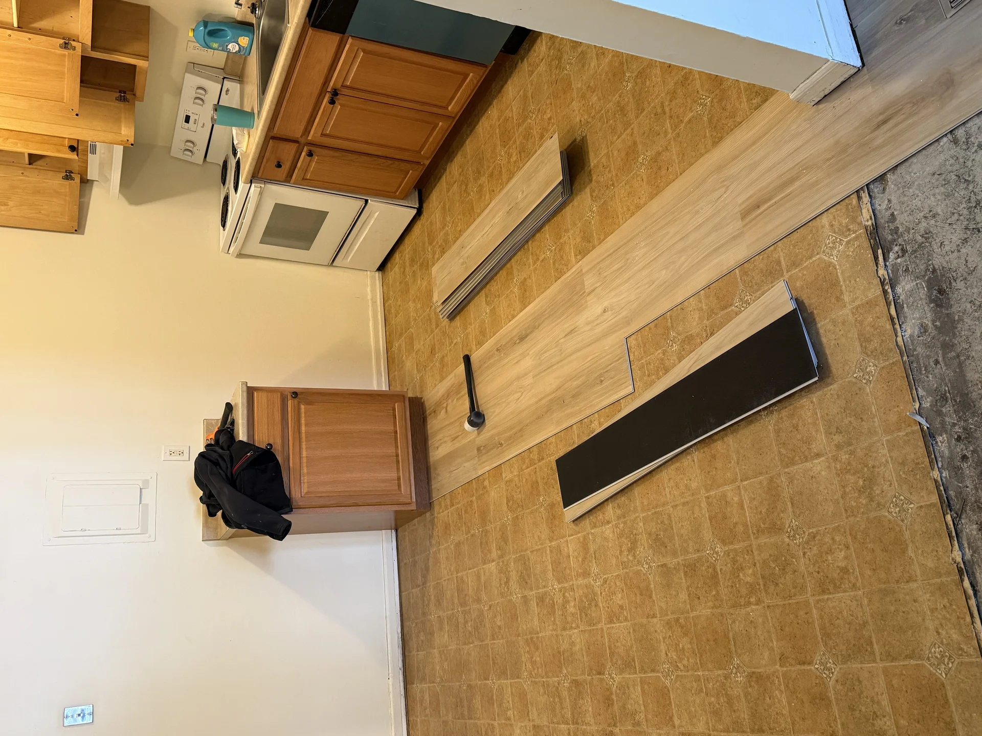 New vinyl plank flooring being installed over an old kitchen floor during a remodel by SF Construction in MetroWest, MA