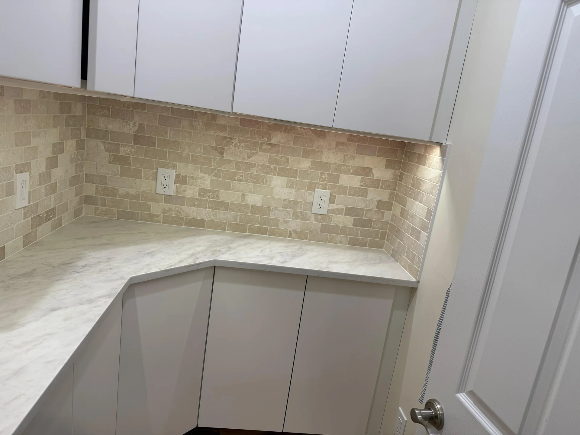 Modern kitchen with white cabinets, marble countertop, travertine subway tile backsplash by SF Construction in Marlborough, M