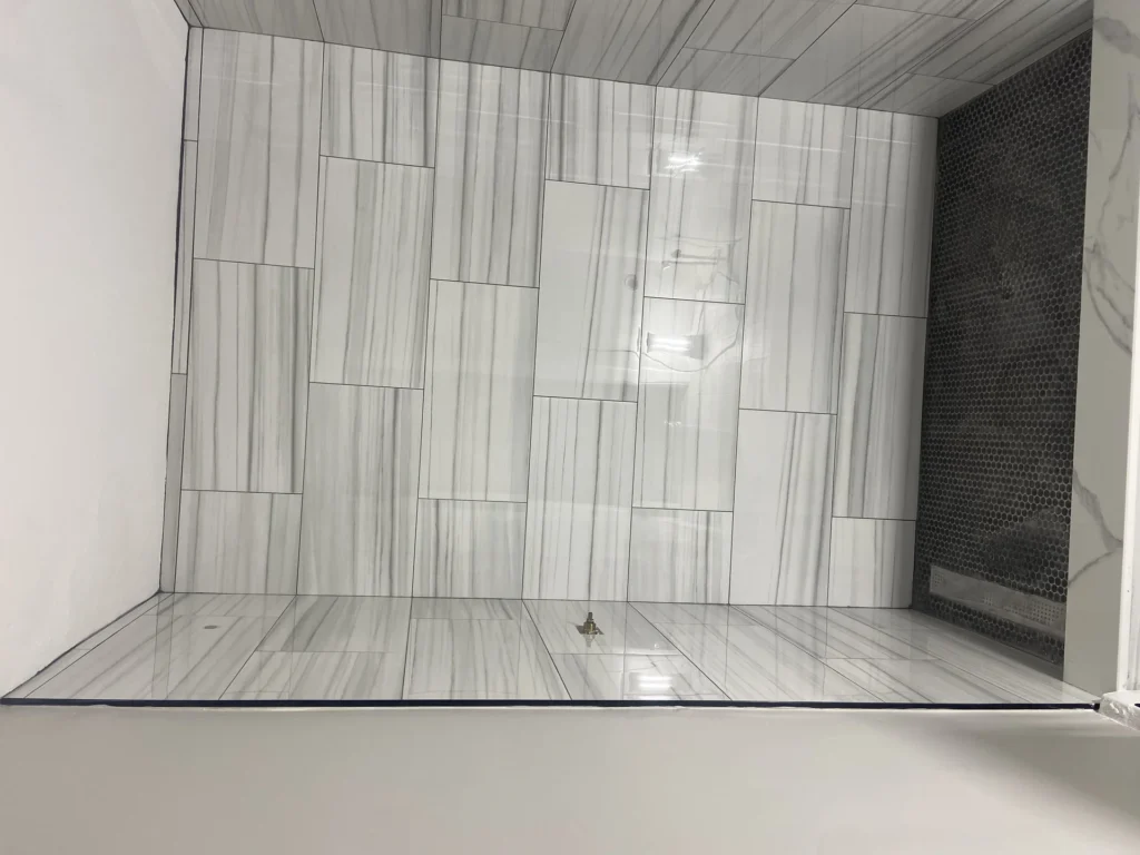 Modern bathroom shower with gray wood-grain tile walls and floor installation by SF Construction in Northborough, MA