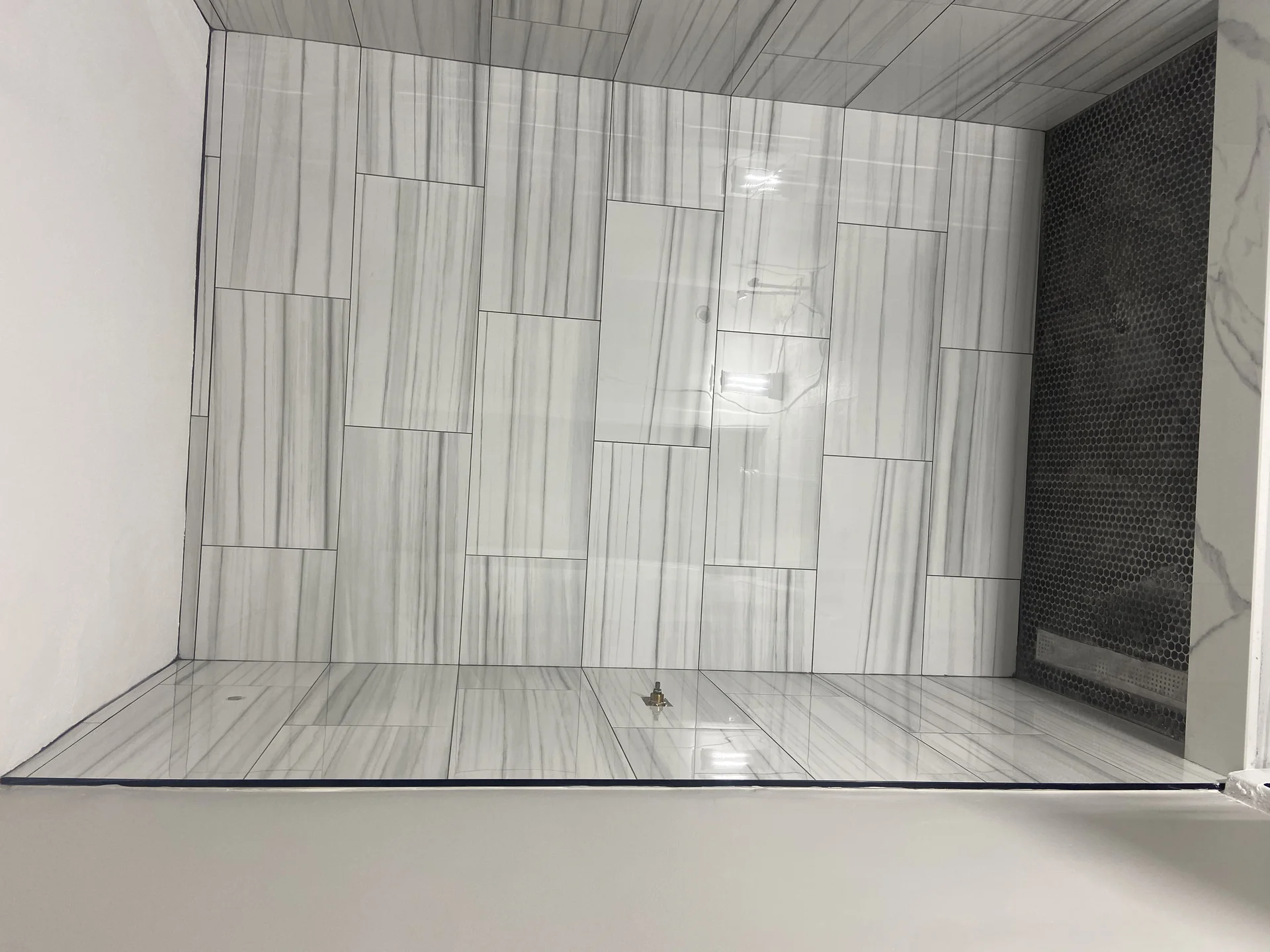 Modern bathroom shower with gray wood-grain tile walls and floor installation by SF Construction in Northborough, MA