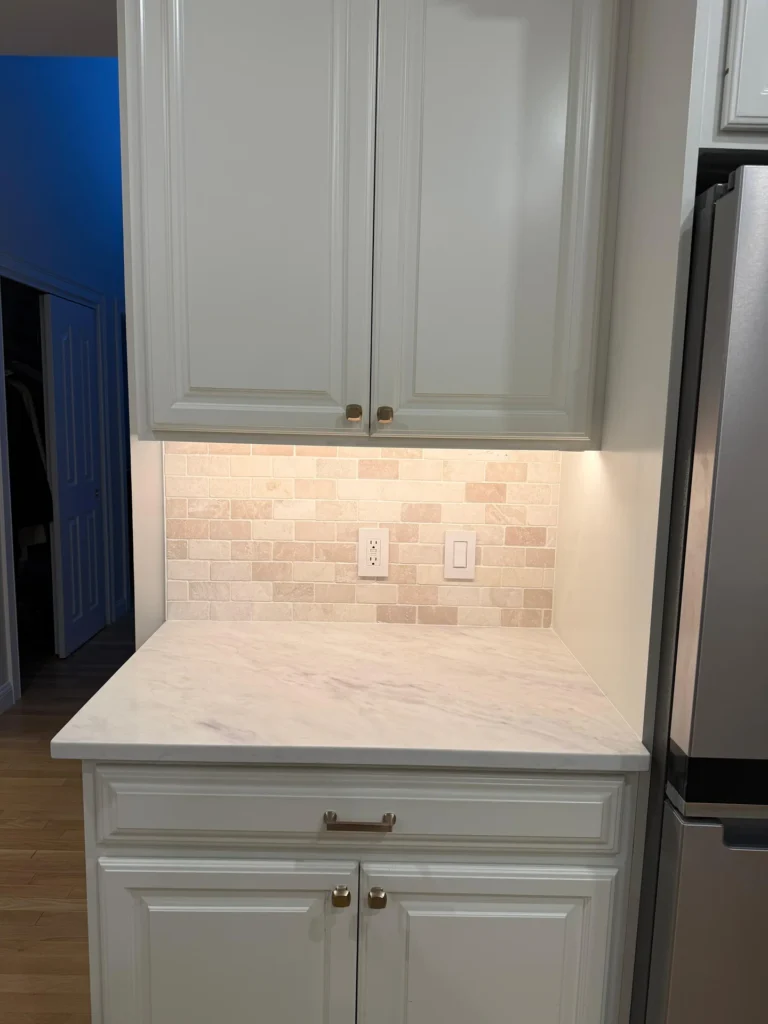 White kitchen cabinets with marble countertop and travertine tile backsplash installation by SF Construction in Framingham, M