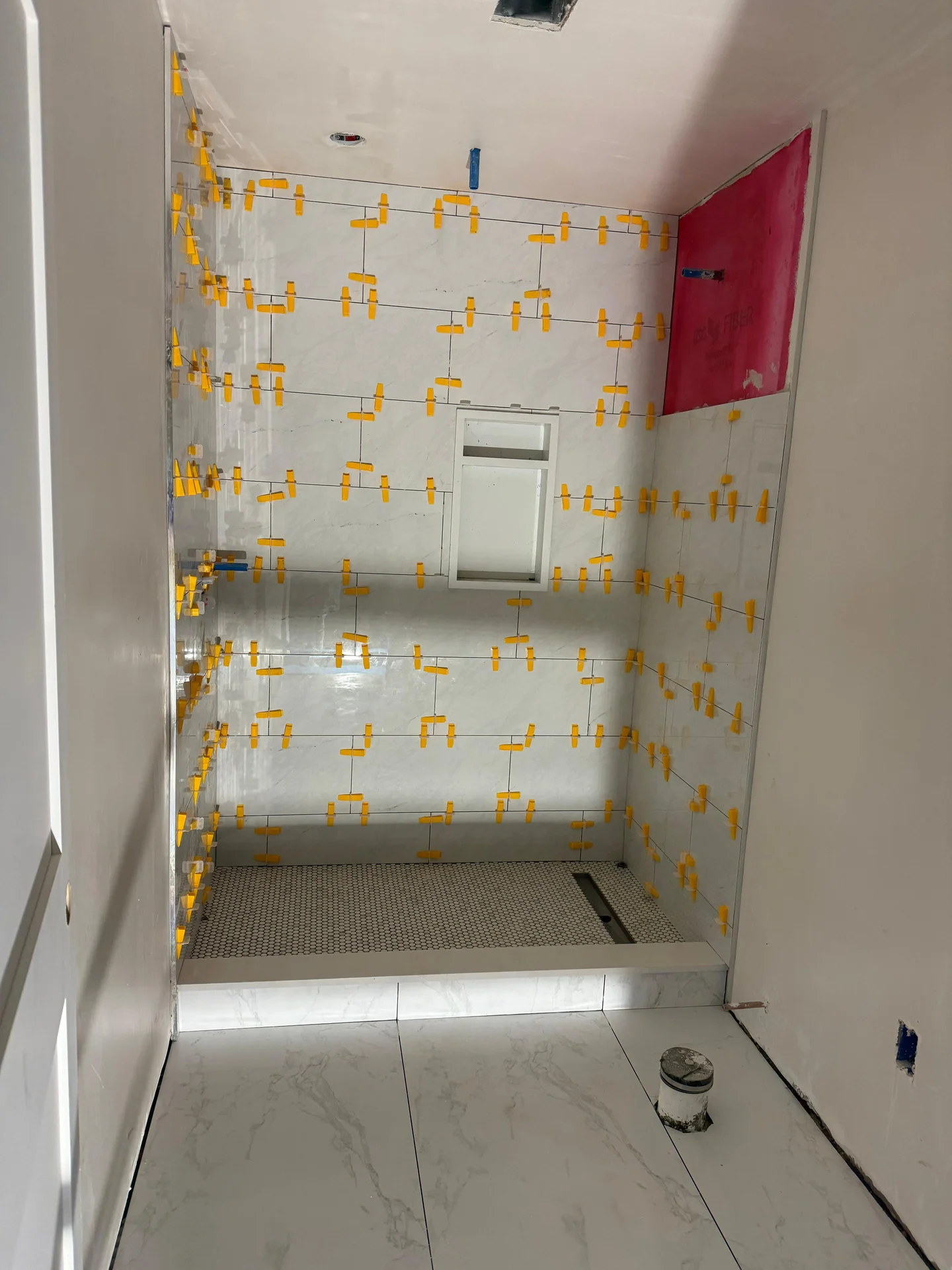Bathroom shower installation with tile layout and yellow spacers applied by SF Construction in Framingham, MA