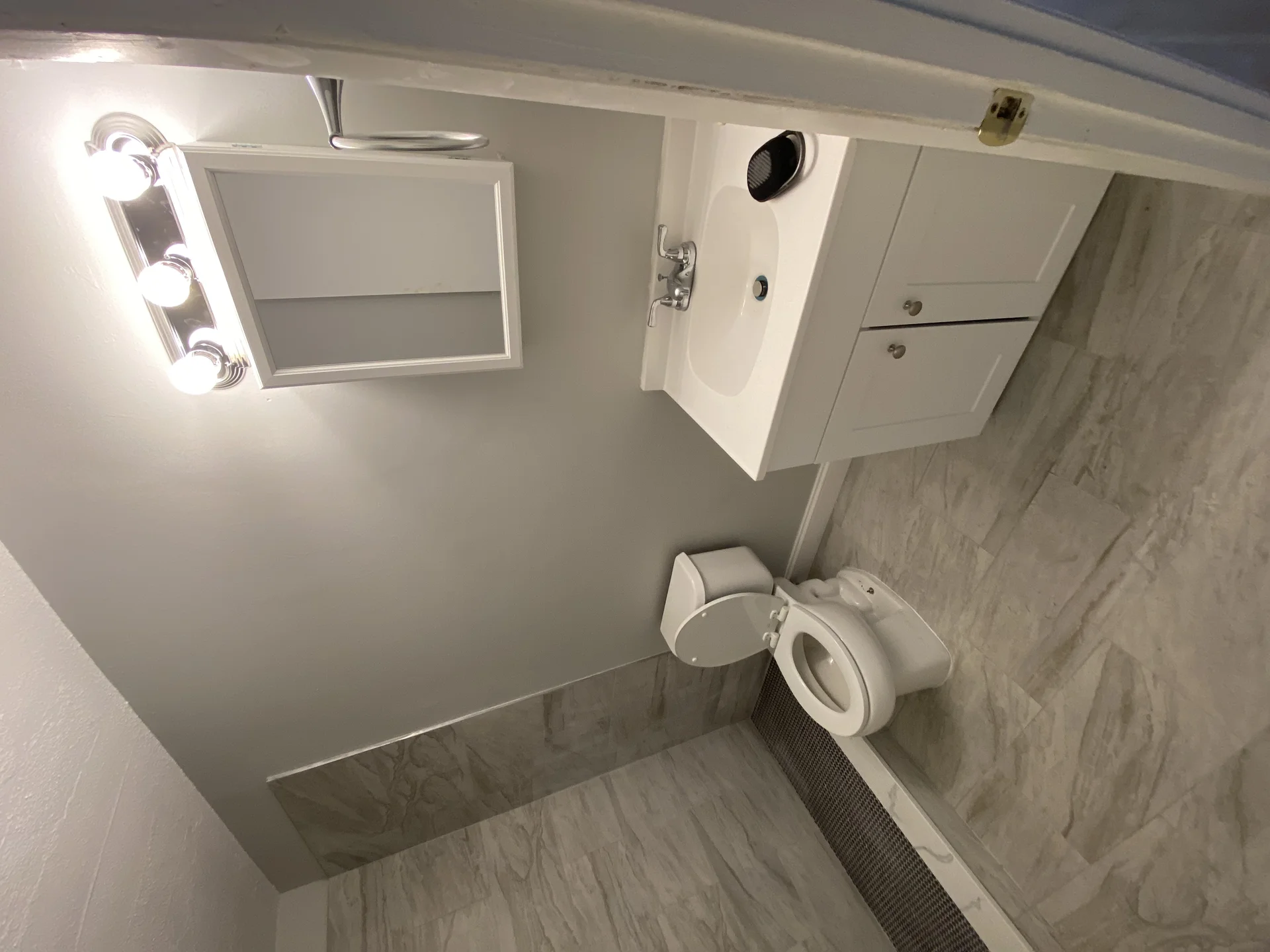 Modern bathroom with white vanity, marble tile flooring, and new fixtures by SF Construction in Hudson, MA
