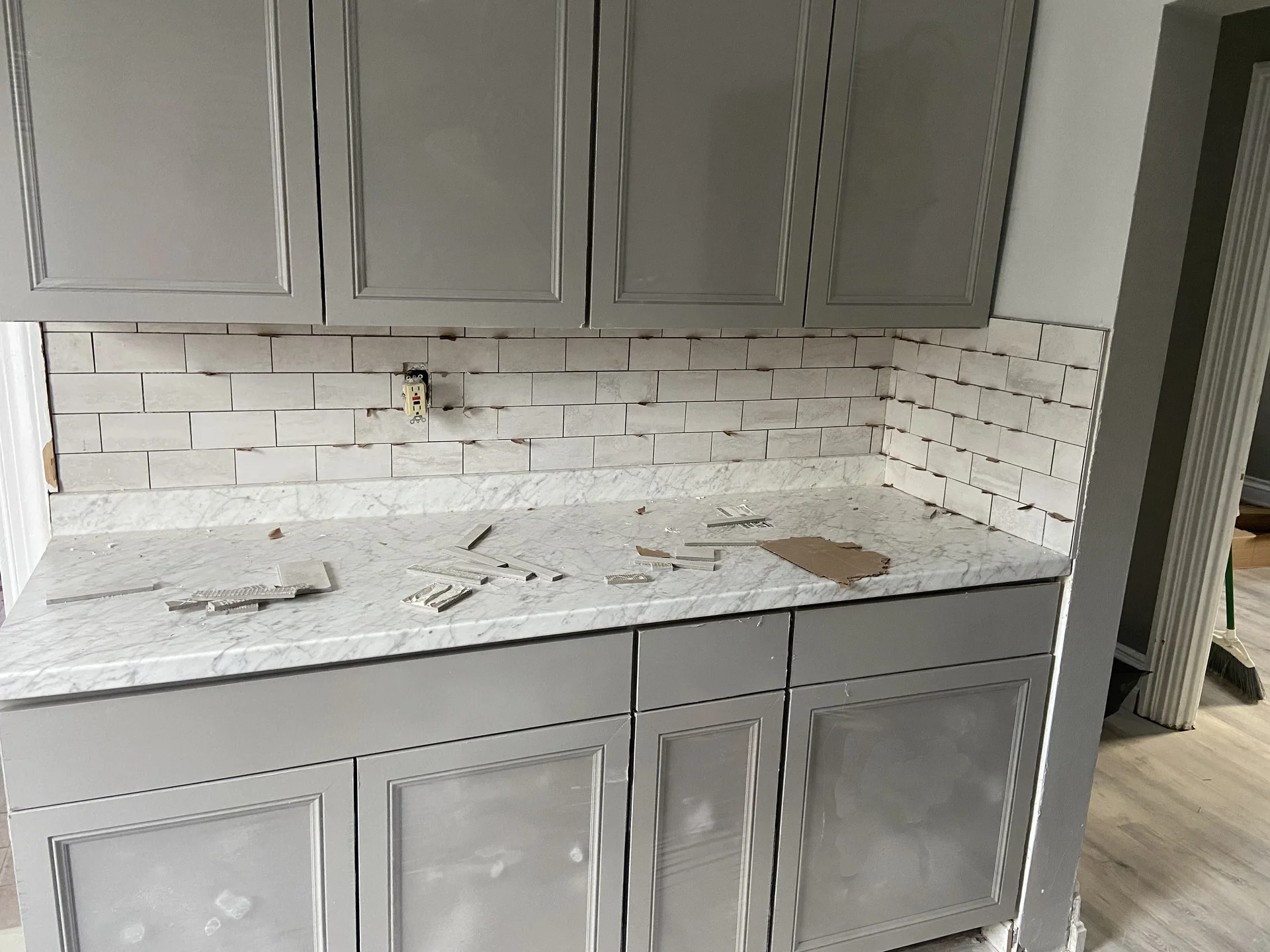 In-progress kitchen with marble countertop, subway tile backsplash, gray cabinetry installation by SF Construction in Sudbury