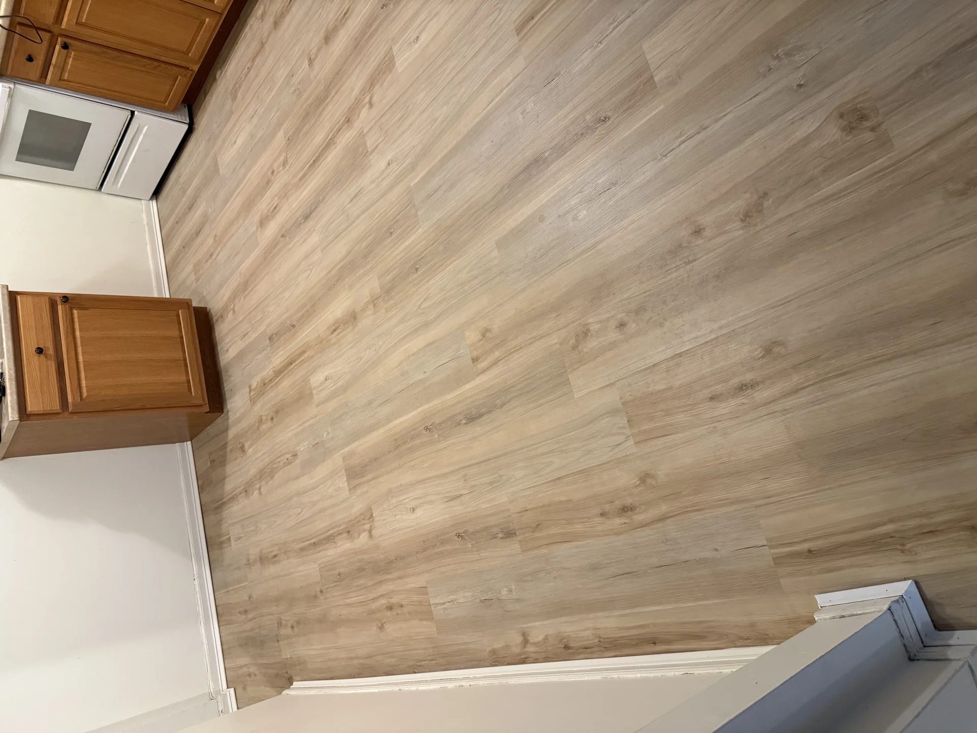 Light wood-tone LVP plank flooring installation in a kitchen by SF Construction in Marlborough, MA