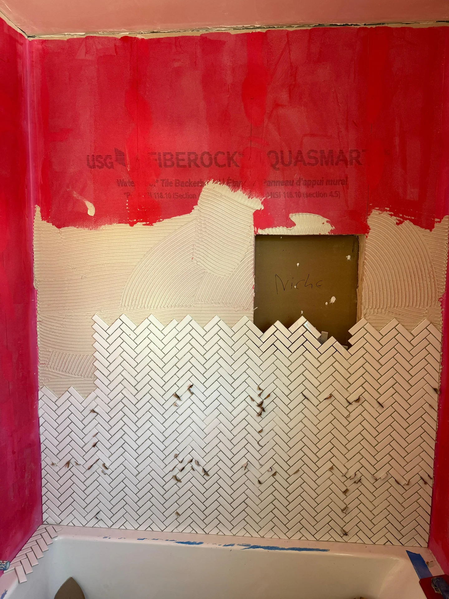 Herringbone tile installation in bathroom with red drywall and natural finish by SF Construction in Northborough, MA