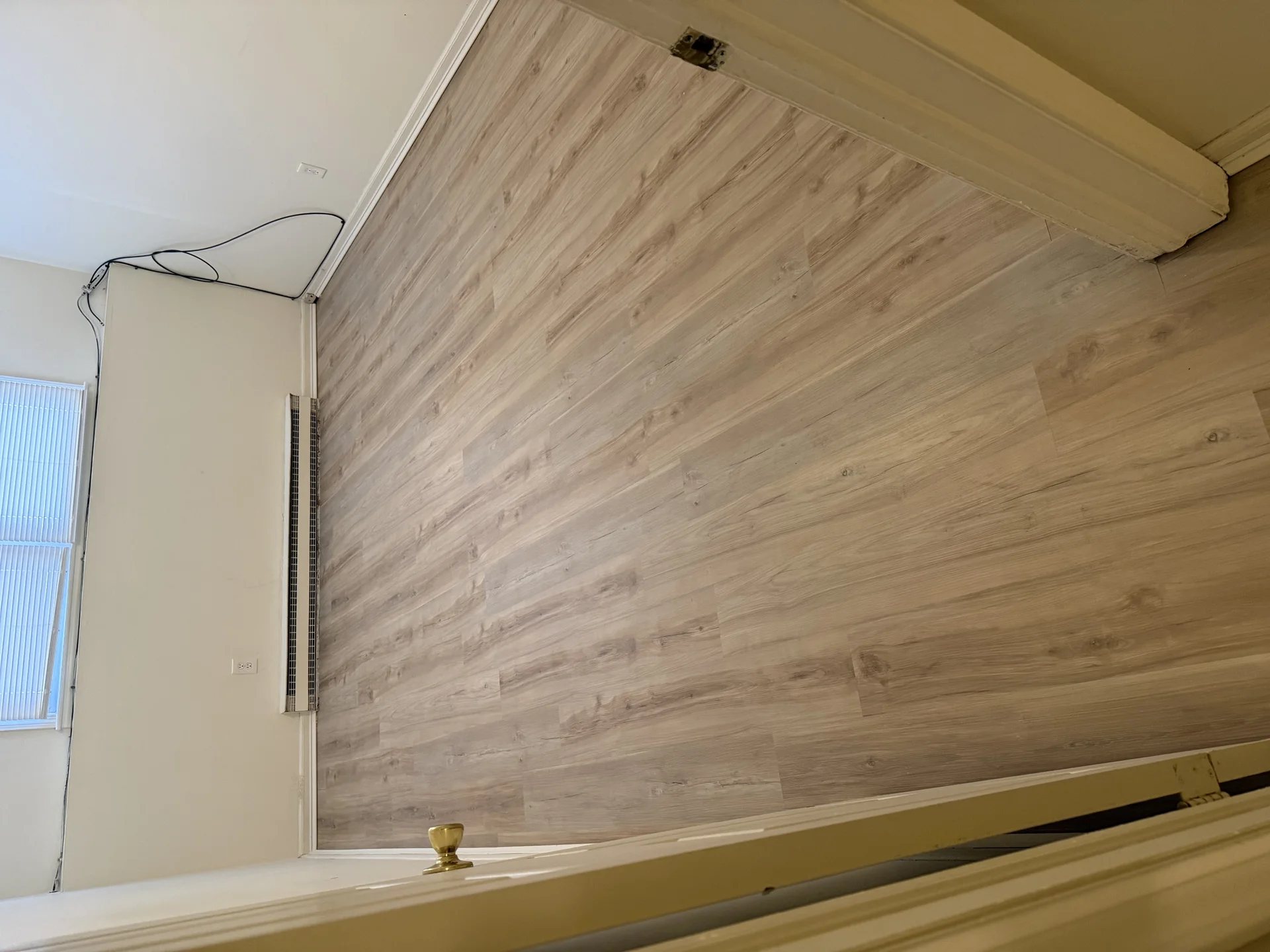 Light wood-grain vinyl plank flooring installation in residential room with white trim by SF Construction in Marlborough, MA