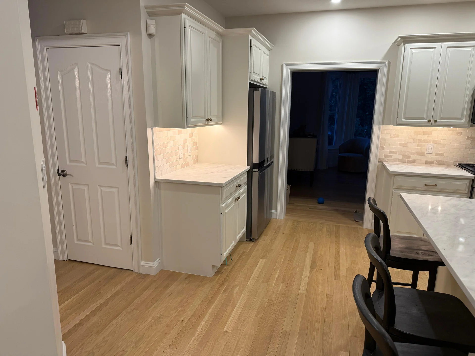 Modern kitchen with white cabinets, tile backsplash, hardwood flooring, stainless steel appliances by SF Construction in West