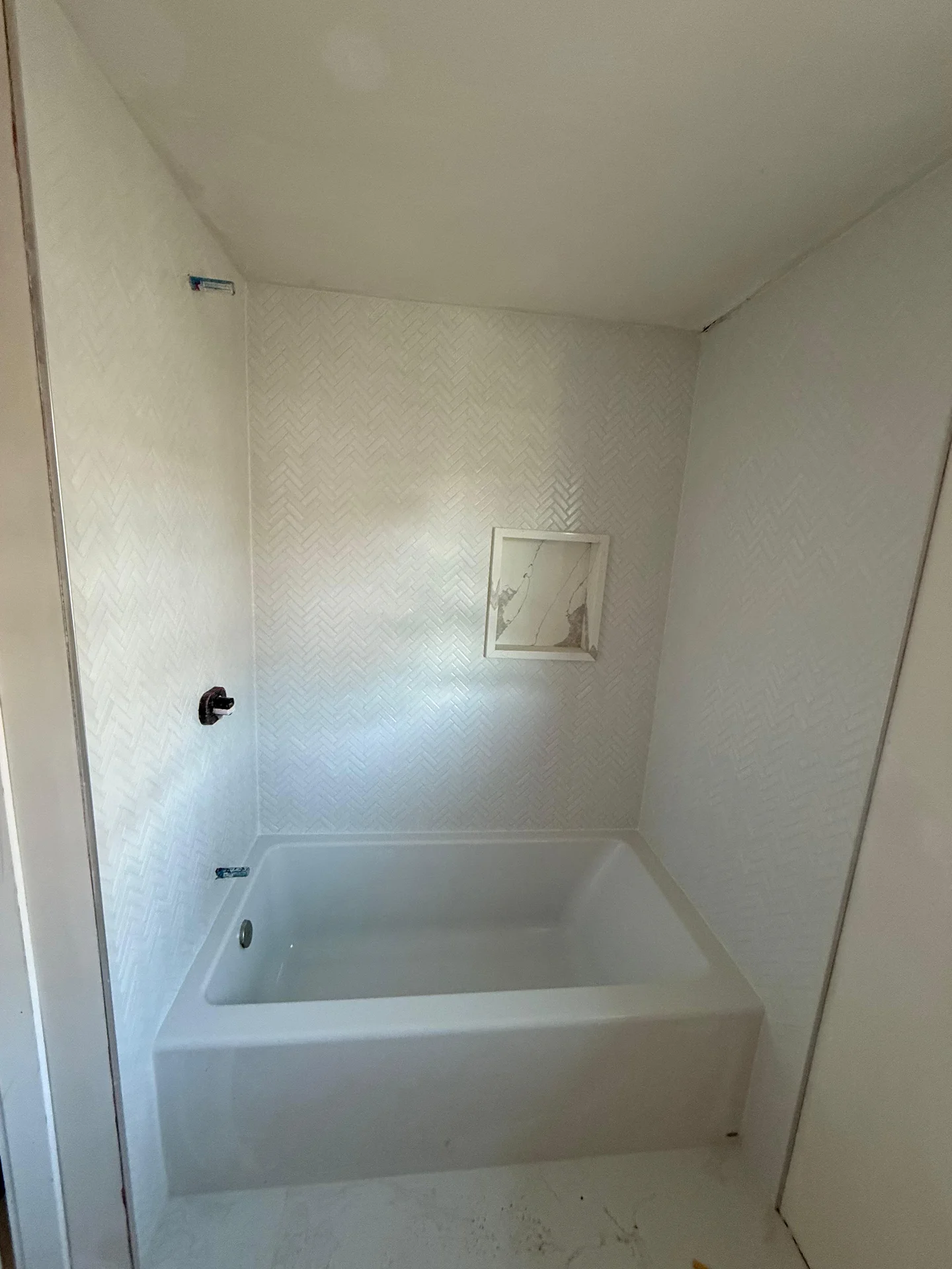 White herringbone tile shower surround with new bathtub installation in progress by SF Construction in Westborough, MA