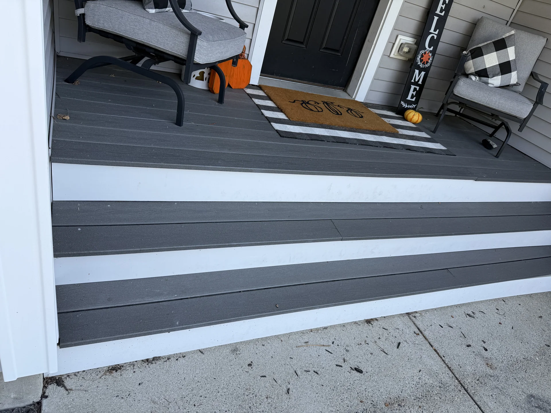 Gray and white striped deck flooring with seasonal porch decorations and furnishings by SF Construction in Westborough, MA