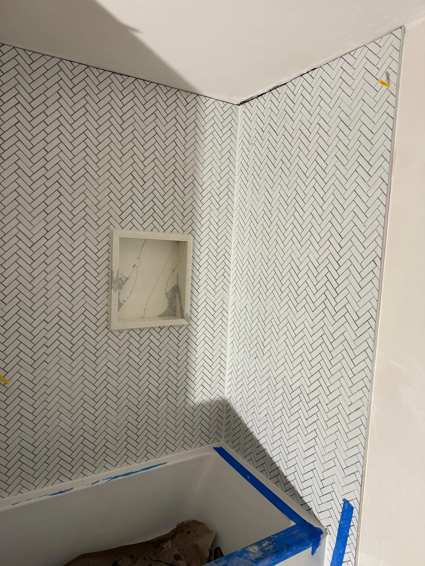 Herringbone white subway tile installation in bathroom shower with niche by SF Construction in Hudson, MA
