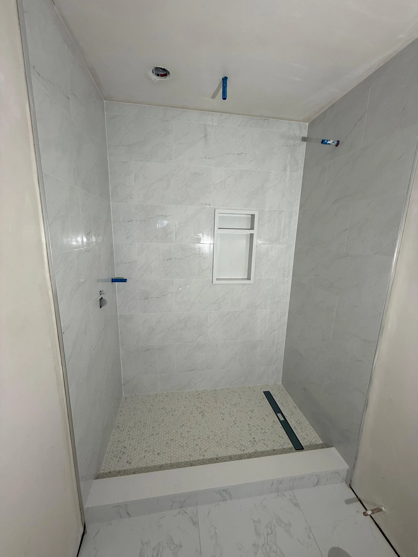 Walk-in shower with marble tile walls and speckled stone floor pan by SF Construction in Hudson, MA