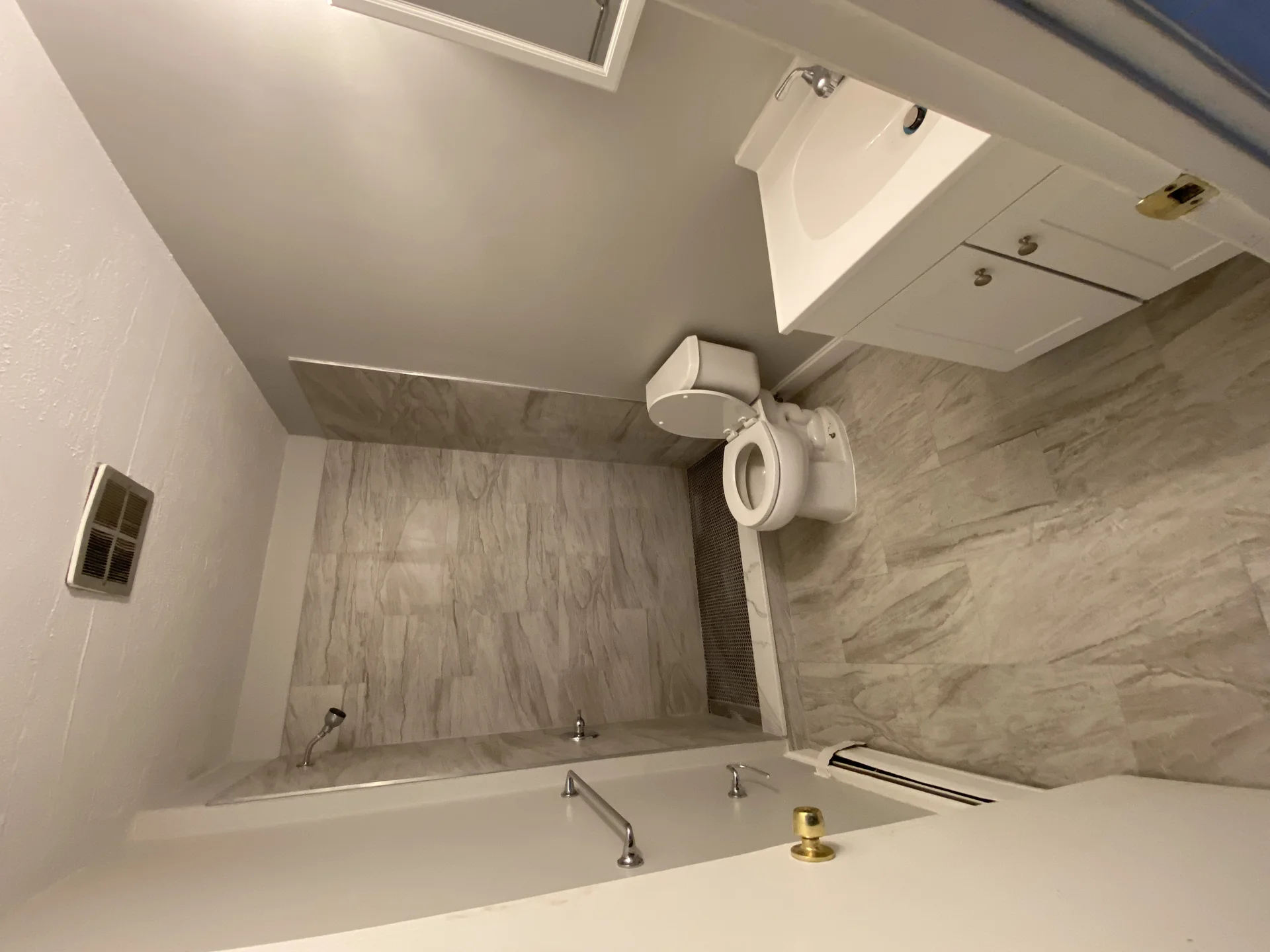 Modern bathroom with gray tile walls, white vanity, and new toilet installation by SF Construction in Framingham, MA