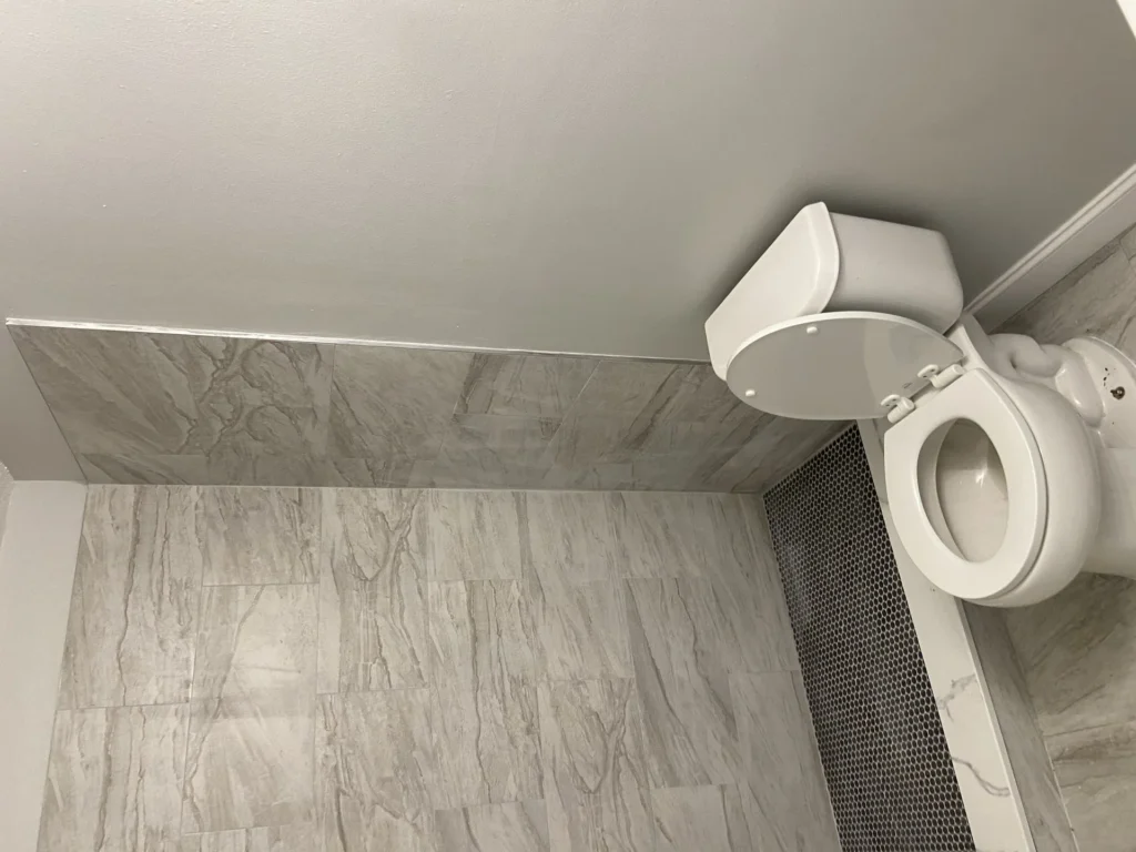 Gray marble-look porcelain tile floor in a remodeled bathroom by SF Construction in MetroWest, MA