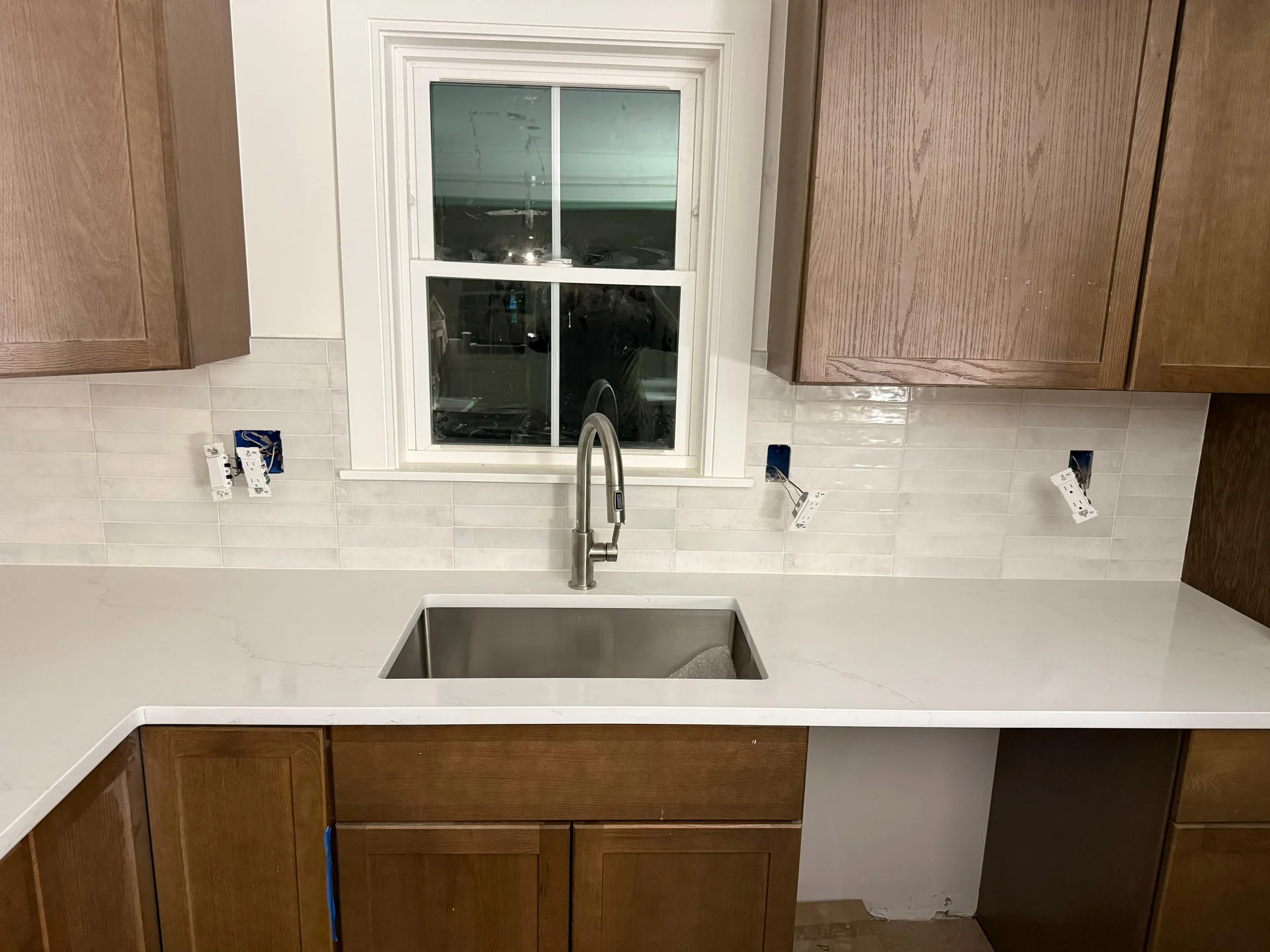 Modern kitchen with white subway tile backsplash, stainless steel sink, and wood cabinets by SF Construction in Westborough,