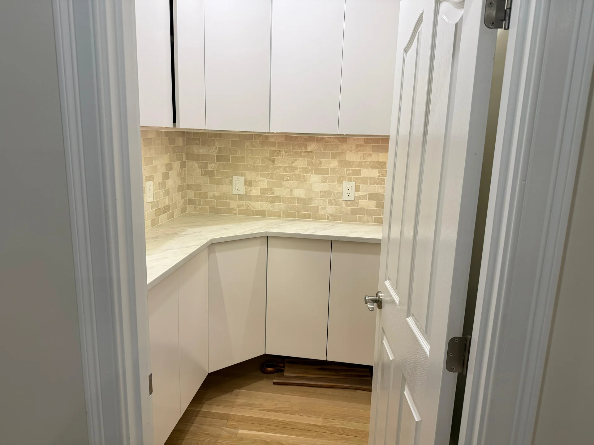 Modern kitchen with white cabinetry, cream subway tile backsplash, and hardwood flooring by SF Construction in Sudbury, MA