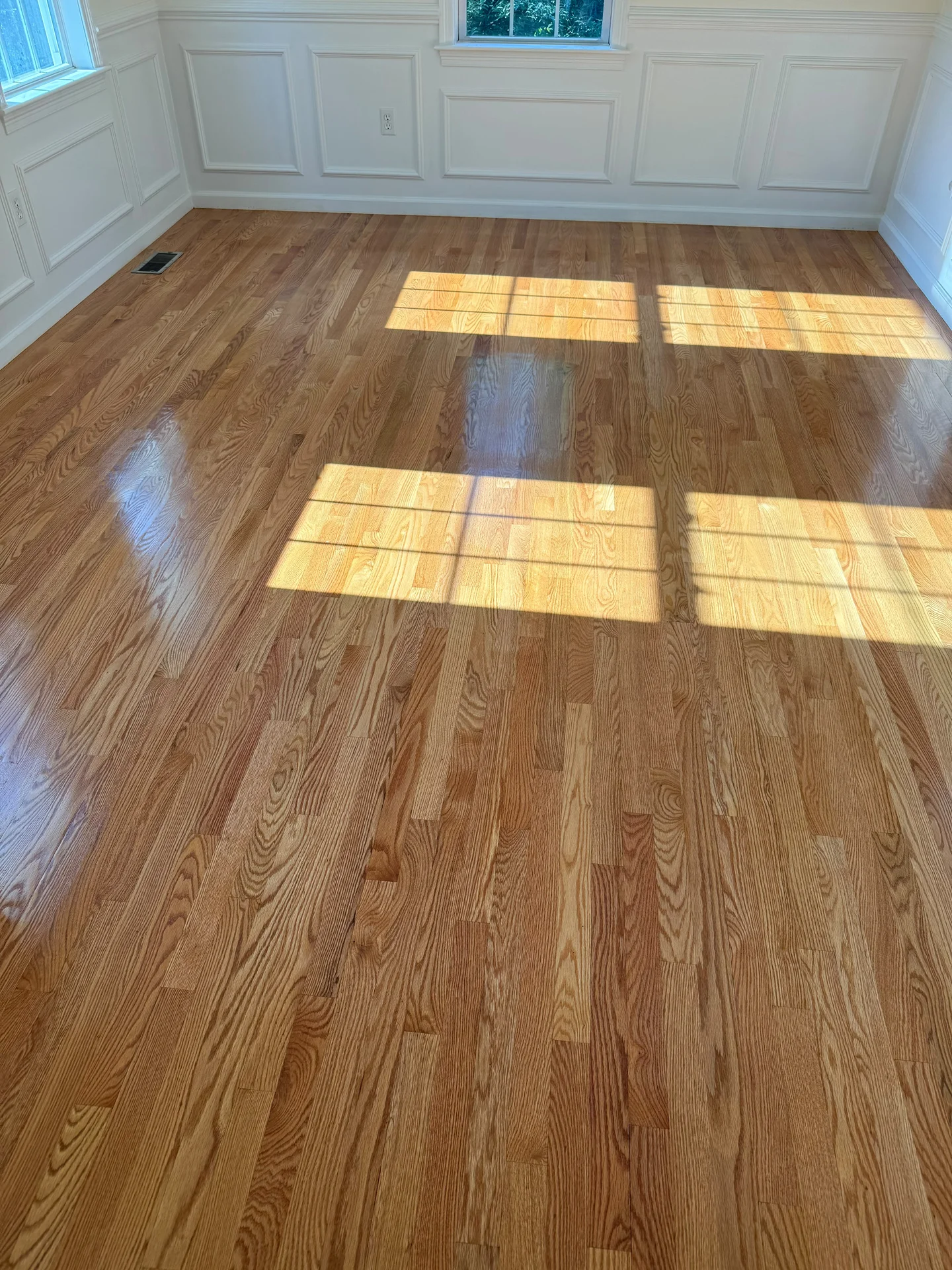 Bright room with newly installed hardwood floors and white wainscoting on walls. by SF Construction in Northborough, MA