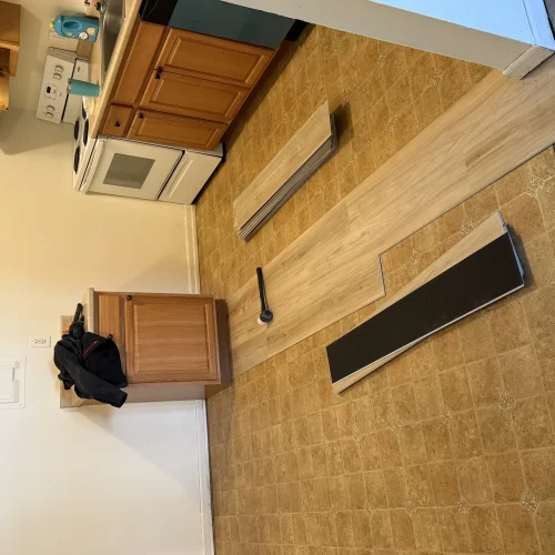 New vinyl plank flooring being installed over an old kitchen floor during a remodel by SF Construction in MetroWest, MA