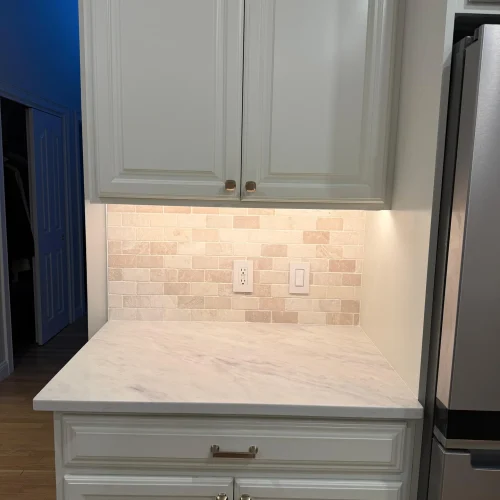 White kitchen cabinets with marble countertop and travertine tile backsplash installation by SF Construction in Framingham, M