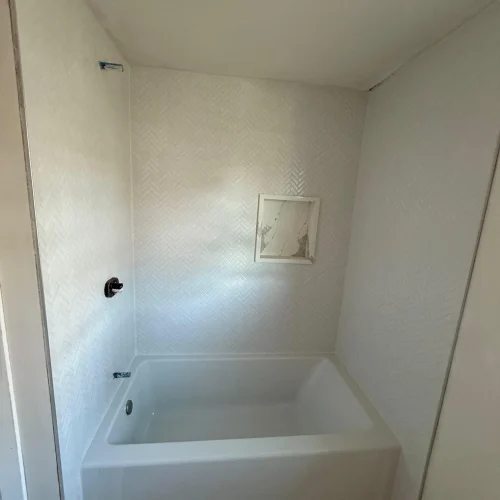 White herringbone tile shower surround with new bathtub installation in progress by SF Construction in Westborough, MA