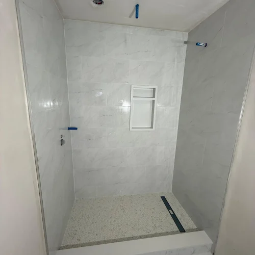 Walk-in shower with marble tile walls and speckled stone floor pan by SF Construction in Hudson, MA