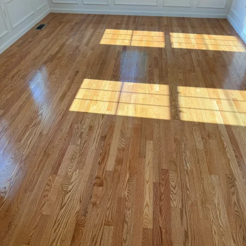 Bright room with newly installed hardwood floors and white wainscoting on walls. by SF Construction in Northborough, MA